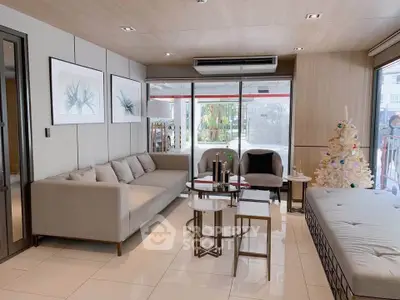 Modern living room with stylish furniture and holiday decor, featuring large windows and elegant design.