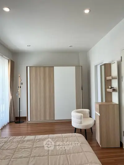 Spacious modern bedroom with elegant wooden flooring and stylish furniture