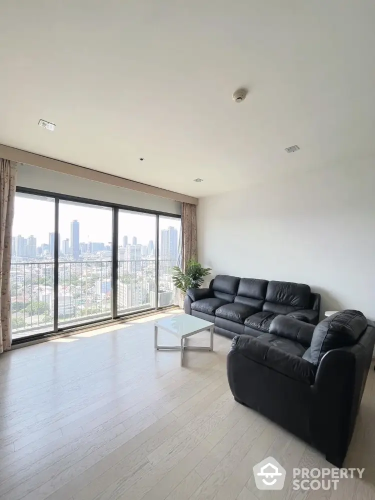 Spacious living room with city view and modern black leather sofas