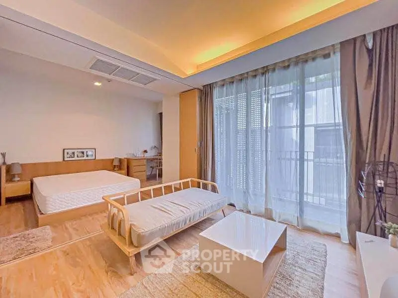 Spacious bedroom with modern decor and large window offering natural light.