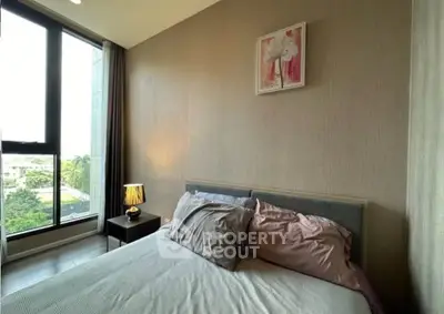 Cozy bedroom with large window and stylish decor in modern apartment.