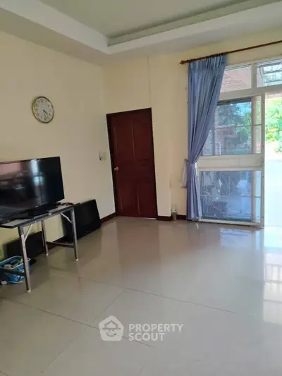 Spacious living room with large window and TV setup, perfect for relaxation and entertainment.