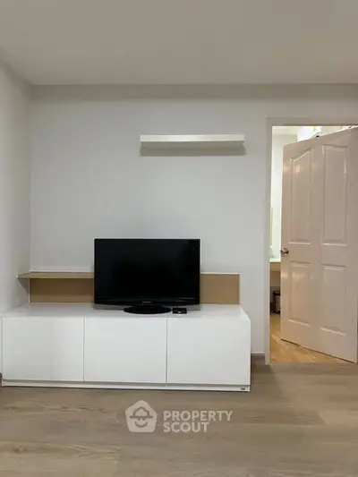 Modern minimalist living room with sleek TV stand and open door to hallway.