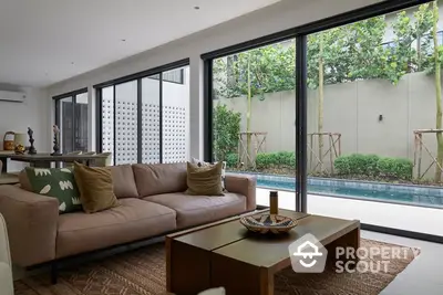 Luxurious living room with pool view, modern decor, and large glass doors for natural light.