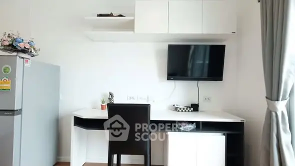 Modern study area with desk, TV, and fridge in a bright apartment