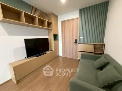 Modern living room with sleek wooden flooring, stylish shelving, and a comfortable green sofa.