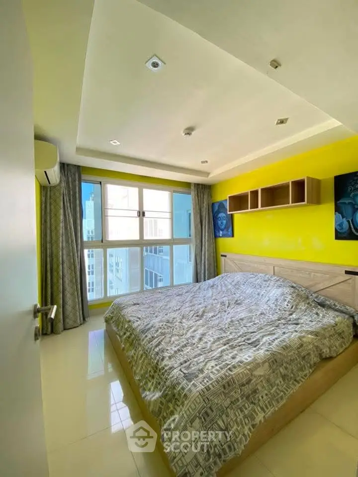 Bright bedroom with large window and modern decor in urban apartment.