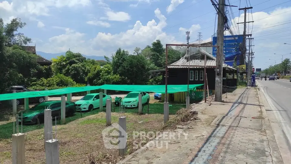 Roadside property with green carport and lush greenery, ideal for commercial use.