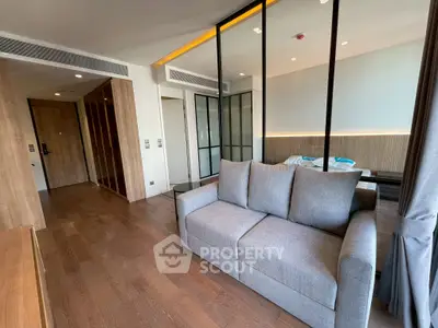 Modern living room with sleek wooden flooring and stylish gray sofa in a contemporary apartment.