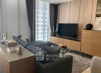 Modern living room with sleek furniture and large windows offering city views.