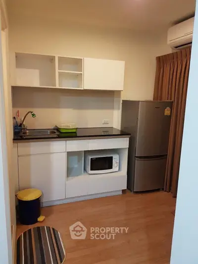 Cozy kitchen with modern appliances and wooden flooring in a compact apartment setting.