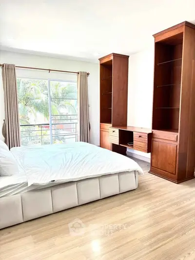 Spacious bedroom with elegant wooden furniture and large window offering a serene view.