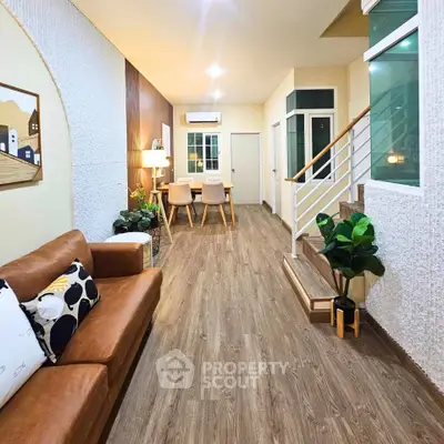 Stylish living room with modern decor and wooden flooring, featuring a cozy seating area and dining space.