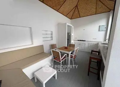 Modern open-layout kitchen with cozy seating and dining area, featuring sleek design and natural light.