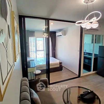 Modern studio apartment with glass partition, cozy living area, and sleek kitchen design.