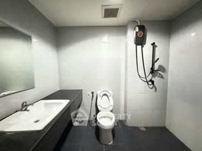 Modern bathroom with sleek fixtures and a spacious layout, featuring a shower and large mirror.