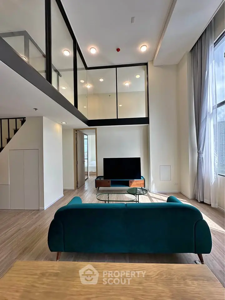 Spacious modern living room with high ceilings and large windows in a stylish apartment.