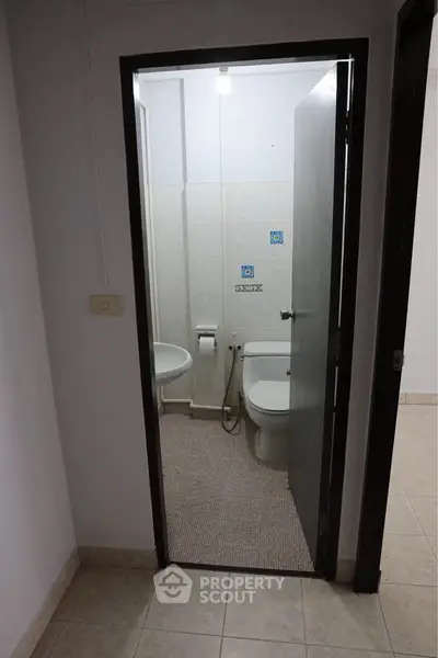 Compact bathroom with tiled floor and basic fixtures in a residential property.