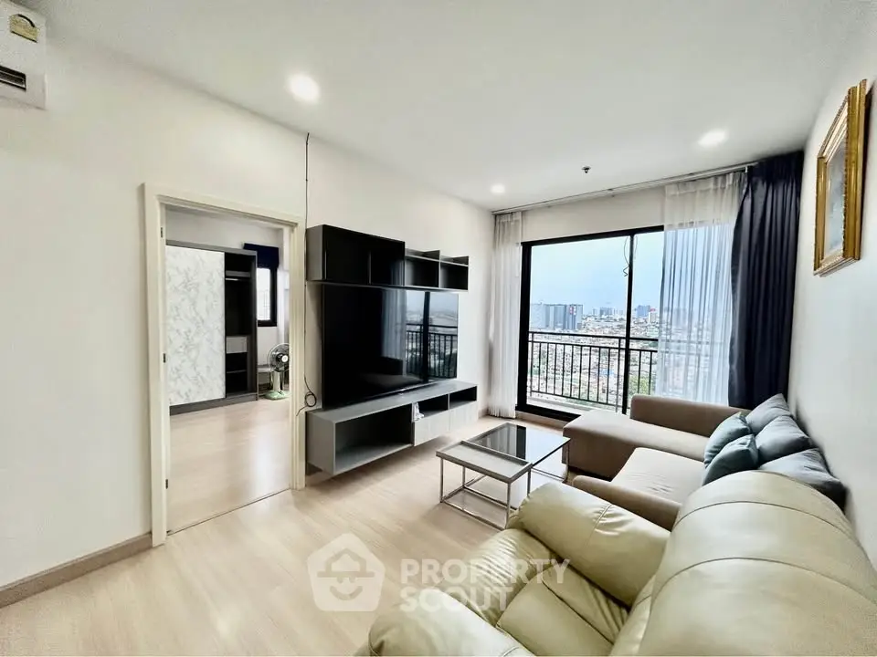 Spacious living room with modern furniture and city view from large window.