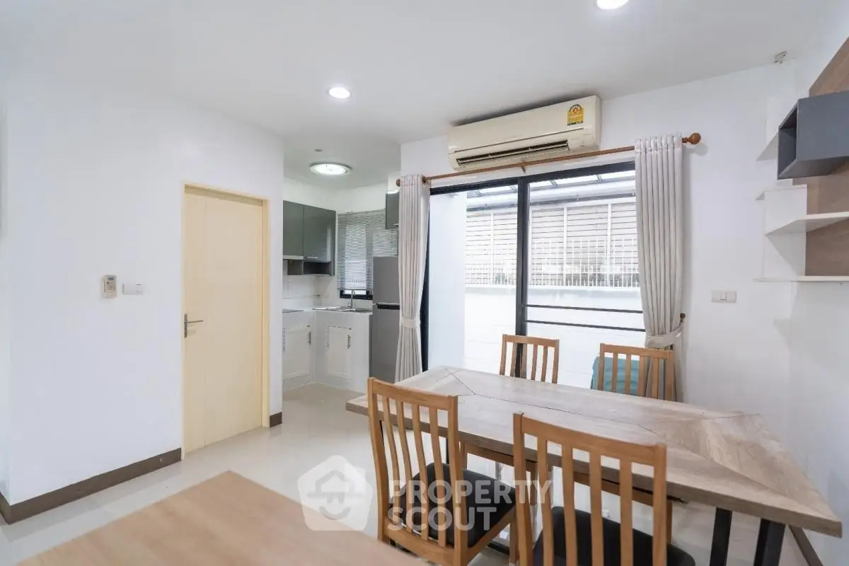Modern dining area with wooden table and chairs, adjacent to a compact kitchen.