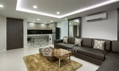 Modern living room with open kitchen, sleek furniture, and ambient lighting.