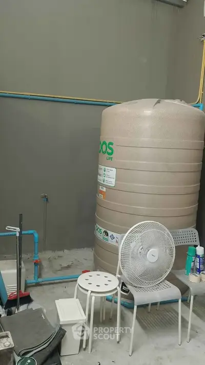 Utility room with water tank and fan, showcasing essential home infrastructure.