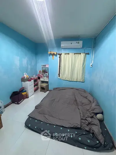 Cozy bedroom with blue walls, air conditioning, and minimalist decor for a comfortable living space.