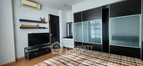 Modern bedroom with sleek furniture and ample storage space, featuring a stylish air conditioner and contemporary decor.