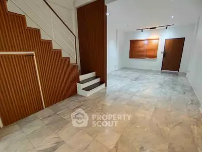 Spacious modern living room with elegant staircase and marble flooring