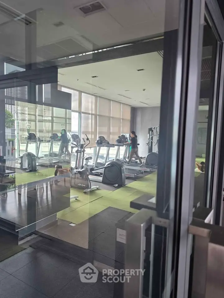 Modern gym with state-of-the-art equipment and large windows in a luxury residential building.