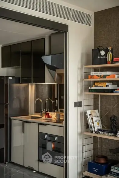 Modern kitchen with sleek cabinetry and built-in oven, adjacent to stylish shelving with books and decor.