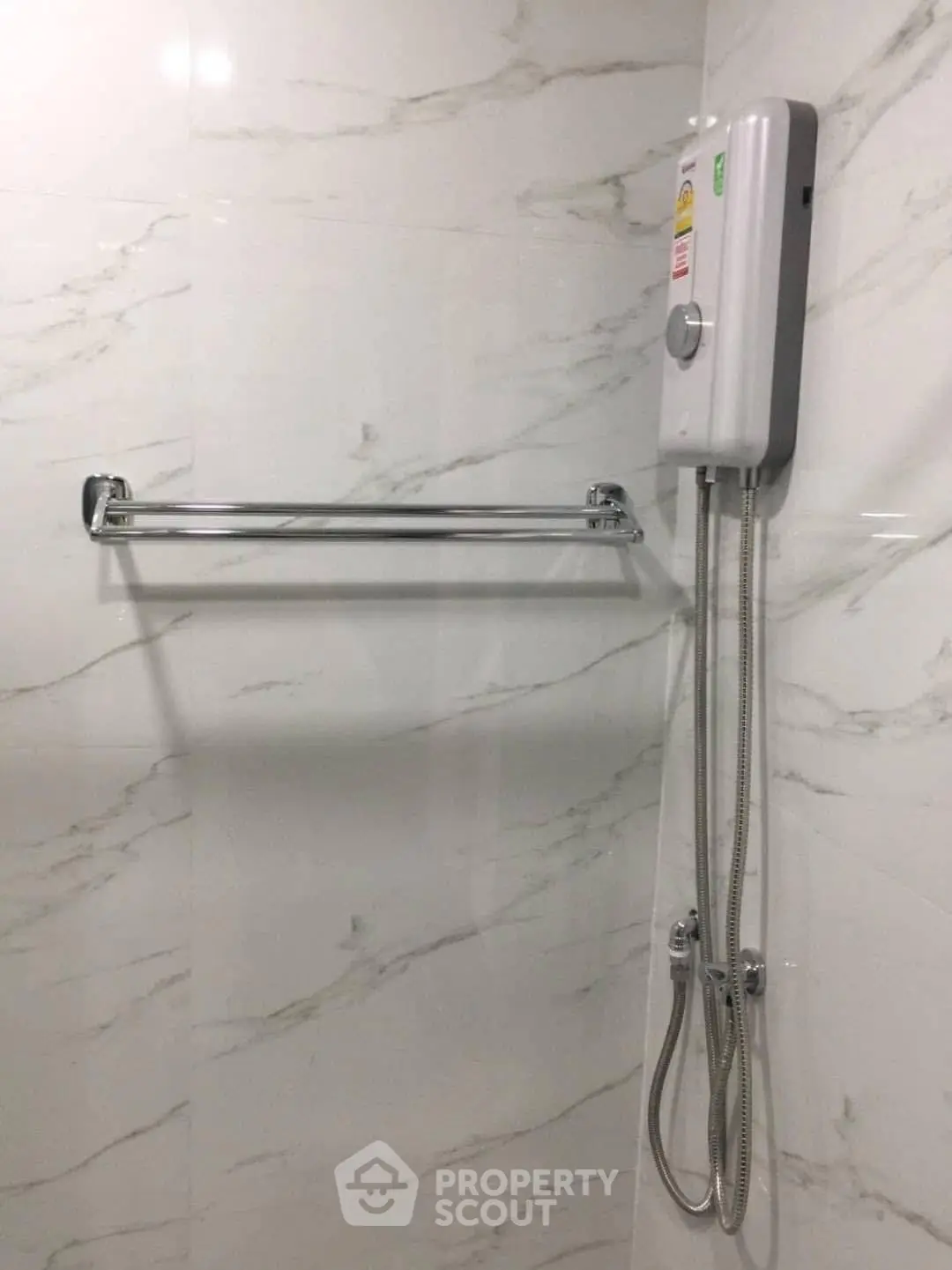 Modern bathroom with sleek shower heater and towel rack on marble wall.
