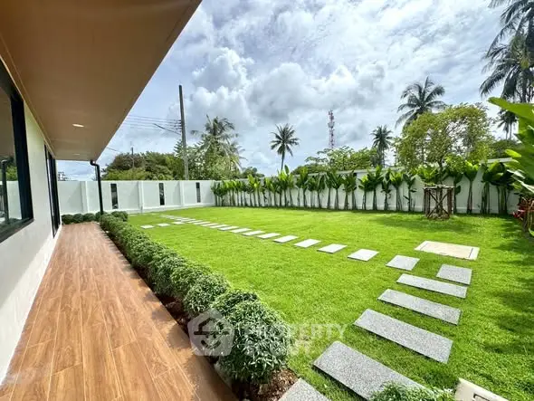 Spacious backyard with lush green lawn and modern landscaping in a tropical setting.