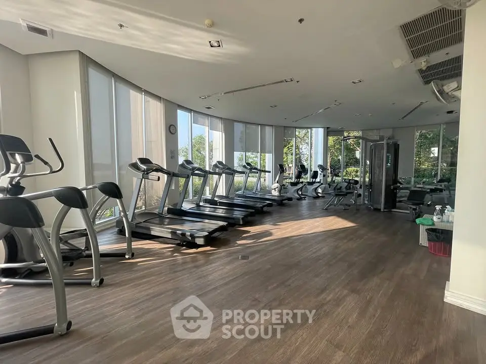 Spacious gym with modern equipment and large windows offering scenic views.