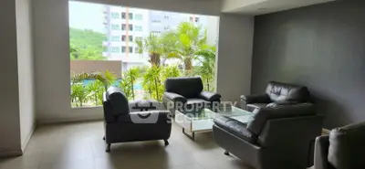 Modern living room with leather sofas and large window overlooking greenery