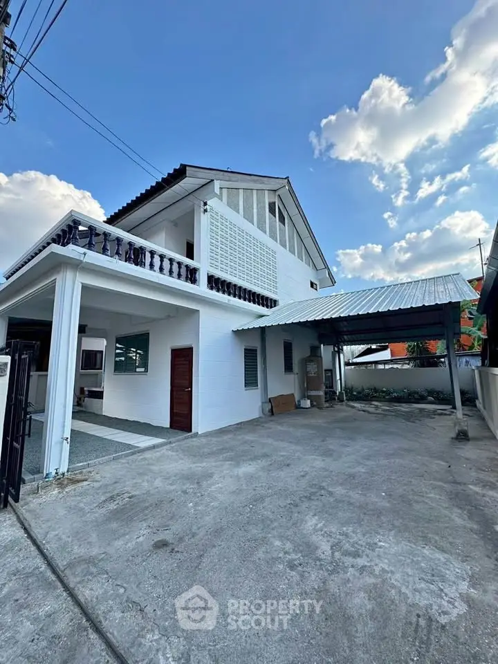 Spacious two-story house with carport and open driveway under a clear blue sky.
