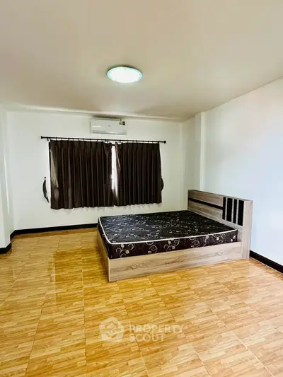 Spacious bedroom with modern design and natural light, featuring a comfortable bed and elegant flooring.