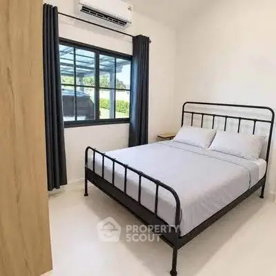 Cozy bedroom with modern metal bed frame and large window for natural light.