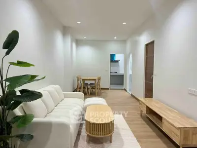 Modern living room with stylish furniture and open layout leading to dining area and kitchen.