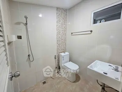 Modern bathroom with sleek fixtures and tiled walls, featuring a shower, toilet, and sink.