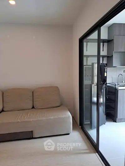 Modern living room with sliding glass door to sleek kitchen area.