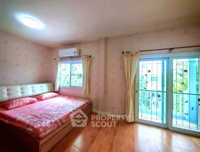 Spacious bedroom with large windows and cozy decor in a modern home.