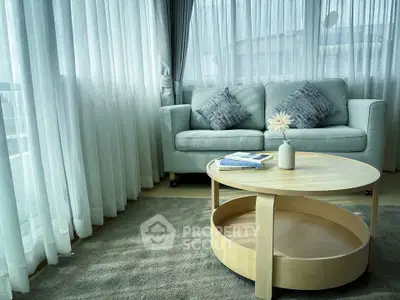 Elegant living room with cozy sofa and stylish coffee table by large windows.