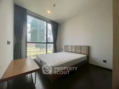 Modern bedroom with large window and city view, featuring a minimalist design and natural light.