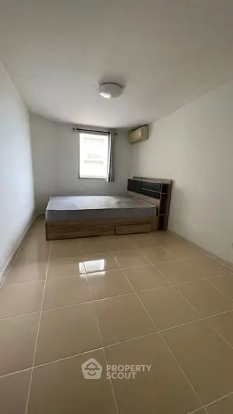 Spacious minimalist bedroom with tiled flooring and natural light.