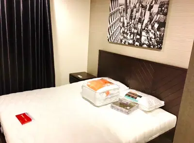 Cozy bedroom with modern decor and cityscape artwork, featuring a comfortable bed and stylish furnishings.