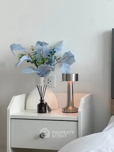Elegant bedroom nightstand with modern lamp and decorative vase, perfect for cozy living.