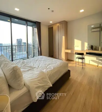 Spacious bedroom with city view and modern furnishings in high-rise apartment.