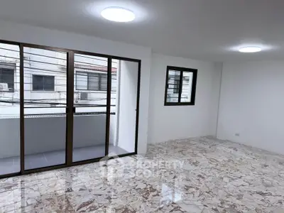 Spacious living room with marble flooring and balcony access in modern apartment.