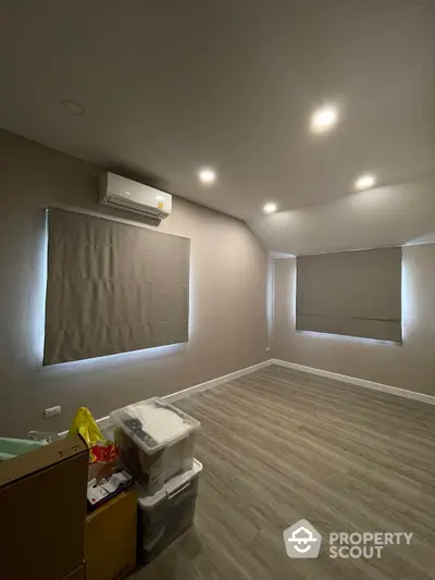 Spacious and modern living area with elegant wood-like flooring, recessed lighting, and a sleek air conditioning unit, ready for personalization.